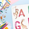 A flat lay of school and craft supplies with a portion of an alphabet mat featuring animals and letters. Náhled obrázku produktu