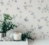 A close-up shot of a candle and a plant on a tray, with floral wallpaper in the background. Produktbild-Vorschau
