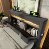 A modern upholstered bed frame with integrated shelving and lighting, featuring charging devices on top. Podgląd zdjęcia produktu
