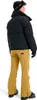 A person wearing a ski outfit, including a black puffer jacket and tan ski pants, posing against a white background. Náhľad obrázku produktu