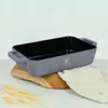 A taupe roasting pan with black interior sits on a wooden board next to wheat stalks and a beige cloth. Náhled obrázku produktu