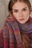 Close-up of a woman wearing a colorful striped scarf and sweater. Produktbild-Vorschau