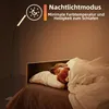 A child sleeping in bed with a teddy bear, illuminated by a dimmable LED floor lamp. Produktbild-Vorschau