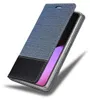 A flip-style phone case with a blue denim-like texture on the cover and a black leather-like material at the bottom, shown open to reveal a phone screen. Podgląd zdjęcia produktu
