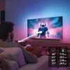 A man is sitting on a couch watching a large TV screen in a dimly lit room with ambient lighting. Voir les images du produit