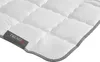 A close-up view of a white quilted blanket with a gray edge and a label. Produktbild-Vorschau