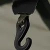 A close-up of a black hook attached to a green and tan strap. Voir les images du produit