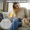 A woman is sitting on a couch with a dog and holding a cup of orange juice. Produktbild-Vorschau