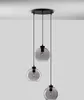 A modern pendant light fixture with three glass globes hanging from a black ceiling mount. Anteprima dell’immagine prodotto