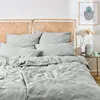 A neatly made bed with light blue musselin bedding and a woven headboard. Produktbild-Vorschau