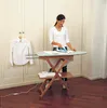 A woman is ironing a shirt in a room with large white cabinets. Produktbild-Vorschau