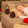A young girl sleeping on a couch with two pinecone-shaped LED candles lit nearby. Produktbild-Vorschau