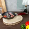 A cast iron frying pan with food ingredients on a wooden board, with kitchen items in the background. Náhľad obrázku produktu