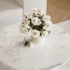 A white marble coffee table with a vase of white flowers and a small detached flower on the table. Produktbild-Vorschau