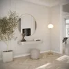A modern entryway with a wall-mounted vanity, a round mirror, a plant, a stool, and a floor lamp. Náhled obrázku produktu