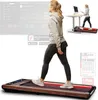 A woman is walking on a treadmill while working at a standing desk. The image also shows a smaller inset of the same scene and graphics related to the product's app. Produktbild-Vorschau