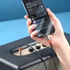 A hand holding a smartphone connected to a speaker via a cable. Anteprima dell’immagine prodotto
