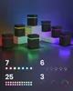 Several black cube-shaped lamps with colored LED lights are displayed on white pedestals with a gradient background. Podgląd zdjęcia produktu
