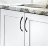 A close-up shot of white cabinet doors with black handles and a marble countertop. Produktbild-Vorschau