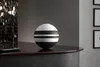 A black and white striped spherical vase sits on a dark countertop next to a faucet. Náhľad obrázku produktu