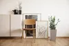 A modern living room scene with a plant pot, chair, and artwork. Náhľad obrázku produktu