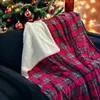 A cozy plaid blanket is draped over a dark armchair in front of a decorated Christmas tree. Produktbild-Vorschau