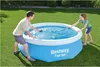 A man and a woman are setting up a blue inflatable pool in a grassy backyard. Produktbild-Vorschau
