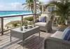 A patio set on a wooden deck overlooking a beach and ocean. Produktbild-Vorschau
