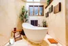 A modern bathroom with a freestanding bathtub, plants, and decorative elements. Produktbild-Vorschau