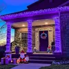 A house porch decorated with purple Christmas lights, including icicle lights along the roofline and lights wrapped around columns. There are also Christmas trees, gifts, and Santa figures as decorations. Produktbild-Vorschau