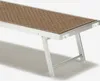 A close-up, angled view of a single beach lounger with a woven brown seat and silver aluminum frame, set against a plain white background. Produktbild-Vorschau