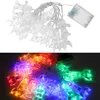A split image showing a string of clear astronaut and rocket-shaped LED lights, first unlit on a white background with a battery pack, and then lit with colorful lights on a dark background. Náhled obrázku produktu
