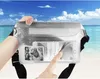 A hand holding a clear waterproof bag with a phone and a photo inside, on a beach with the ocean and sky in the background. Náhled obrázku produktu