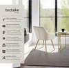 A cream-colored chair with gold legs is placed in a room with a large window and a rug. Produktbild-Vorschau