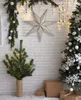 A festive Christmas scene with a large star decoration, a small Christmas tree, and a larger decorated Christmas tree. Anteprima dell’immagine prodotto