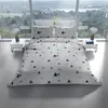 A bed with white and green patterned bedding is set up in a modern room with large windows overlooking a scenic landscape. Produktbild-Vorschau