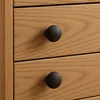 A close-up view of two black knobs on a wooden dresser. Produktbild-Vorschau