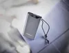 A gray power bank with a digital display showing '90%' is placed on a blue surface, with a blurred background of white and light gray fabric. Voir les images du produit