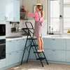 A woman is using a step ladder in a kitchen. Podgląd zdjęcia produktu