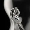 A close-up of a white wireless earbud inserted into a metallic ear sculpture. Náhled obrázku produktu