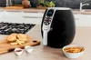 An air fryer on a kitchen counter with ingredients for fries. Podgląd zdjęcia produktu
