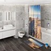 A modern bathroom with marble-effect tiles, a white vanity with a sink, a toilet, a bathtub, and a shower curtain with a beach scene. Produktbild-Vorschau