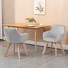 Two gray upholstered dining chairs with wooden legs are placed around a wooden dining table in a room with wood-paneled walls. Podgląd zdjęcia produktu