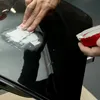 A person is applying a white paste to a black surface with a spatula. Anteprima dell’immagine prodotto