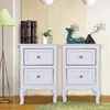 Two white bedside tables with drawers are shown in a room with a patterned wall and a floor lamp. Produktbild-Vorschau