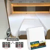 A bedroom in a camper van with beds made up with white sheets, and a package of sheets in the foreground. Produktbild-Vorschau
