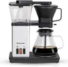 A silver and black filter coffee machine with a glass carafe filled with coffee, placed on a black base. Produktbild-Vorschau