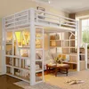 A loft bed with integrated shelves and stairs, set up in a bedroom with a sofa and coffee table. Voir les images du produit