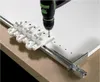 A drill is being used with a jig to drill holes in a white surface. Produktbild-Vorschau