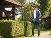 A man is trimming a hedge with an electric hedge trimmer in a garden setting. Náhled obrázku produktu